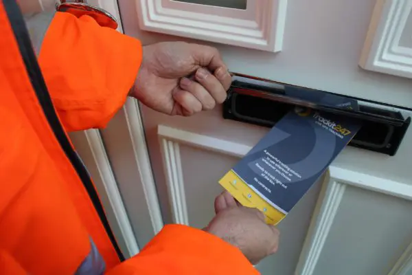 A leaflet distributor placing a pamphlet through a mail slot
